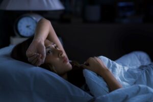 Unhappy woman lying awake in bed at night 